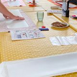 The workshop table: fabric panels, instructions and a plate of biscuits