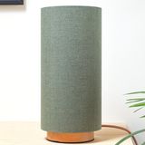 The sage green linen slim lamp on its wooden base