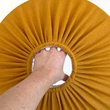 A hand through the top of a pleated mustard scallop shade