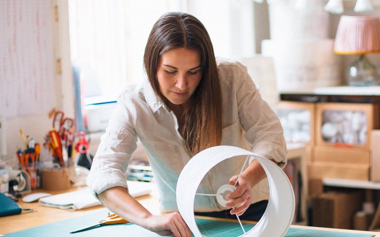 Jo at her studio bench, holding a drum lampshade frame