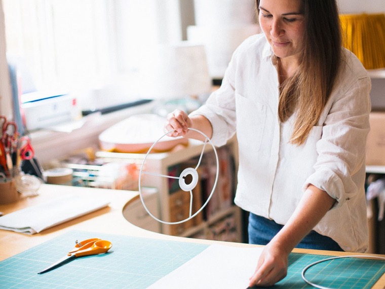 Rolling the fabric round the lampshade rings at the workshop table